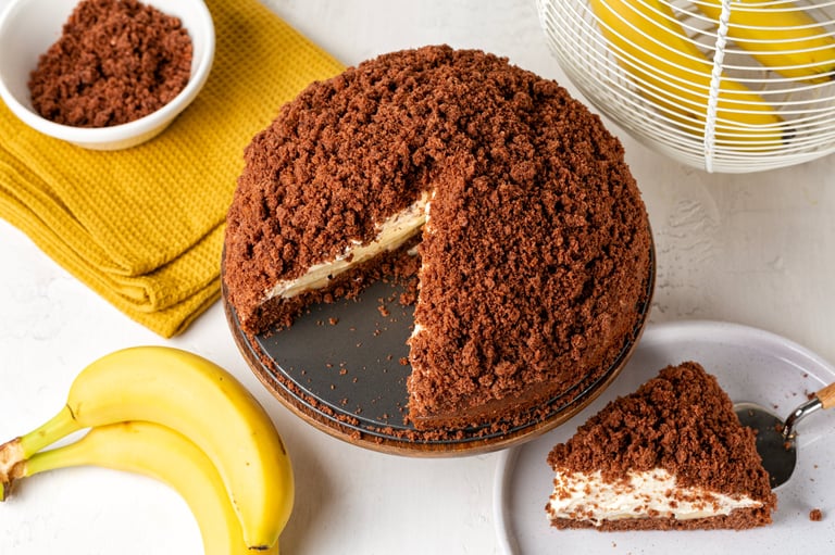 High angle view of homemade german chocolate mole cake coat with crumbs, stuffed with bananas, whipped cream