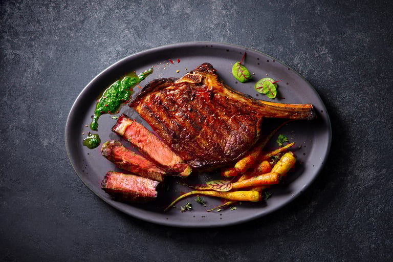 Beef tomahawk steak on bone with roasted carrots and chimichurri sauce