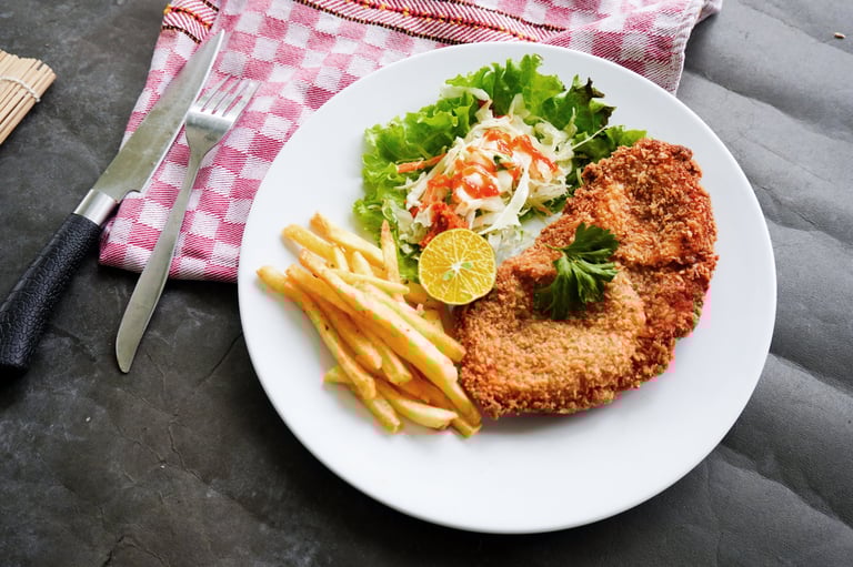 Chicken schnitzel is made from chicken breast, served with French fries, lemon, vegetable salad and sauce
