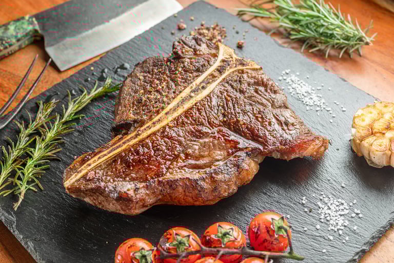 Grilled T-bone steak with seasonings on slate serving plate