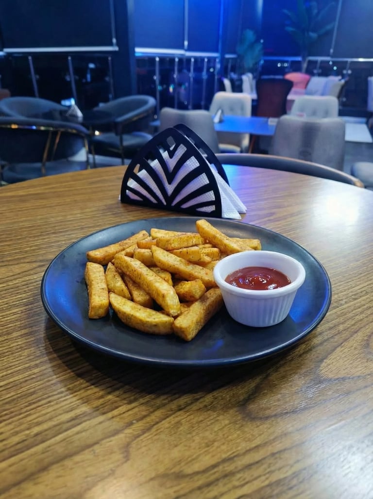 A black plate of golden fried potato wedges with a small bowl of ketchup on a wooden table in a modern restaurant setting