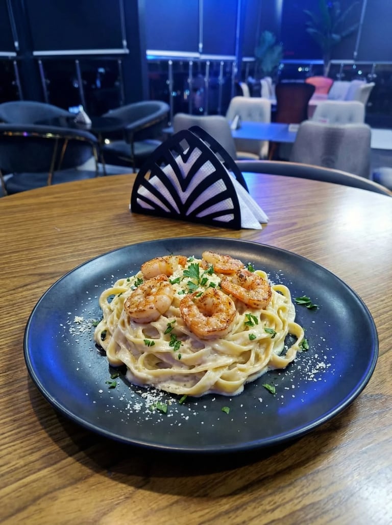 Plated pasta with shrimp and garnish on dark plate at modern restaurant with blue-lit interior