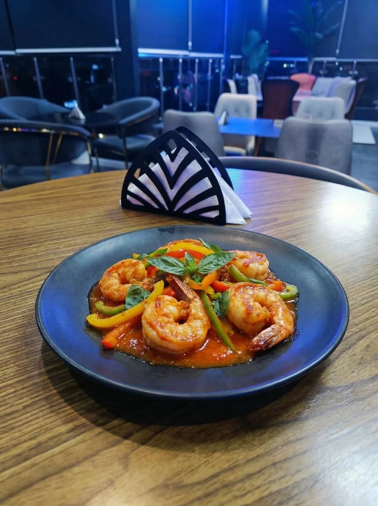 Plated sautéed shrimp with yellow peppers and basil in red sauce on a blue plate at a modern restaurant with city views