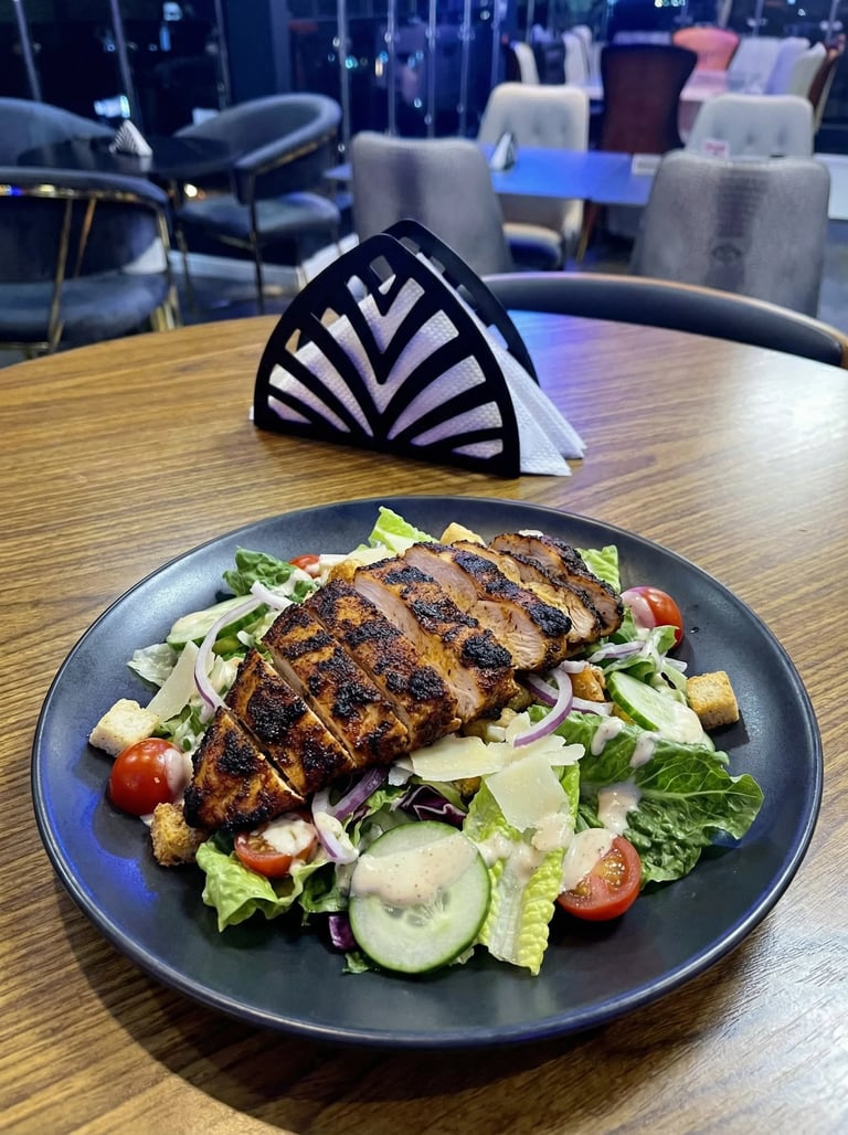 Grilled chicken salad with fresh greens, tomatoes, and cucumber on a dark plate in a restaurant setting
