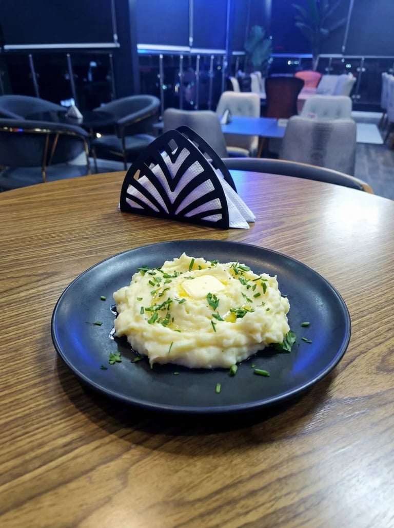 Mashed potatoes with green onions on a dark blue plate at a wooden table in a modern restaurant lounge