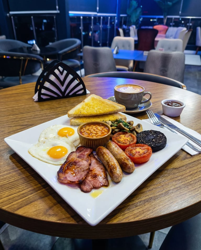 Full English breakfast on white plate at table in cafe with coffee cup and cornered setting in background